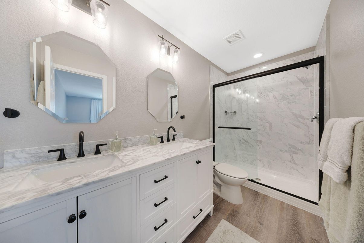 Bathroom, Dual Sink Vanities, Glass Shower, Interior, Marble Walls, Recessed Lighting, Wood Texture Flooring