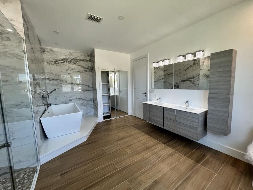 Bathroom, Dual Sink Vanities, Free Standing Baths, Glass Shower, Interior, Marble Walls, Recessed Lighting, Wood Texture Flooring