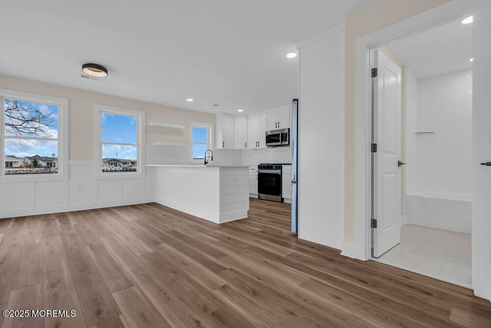 Empty room, Interior, Kitchen, Recessed Lighting, Stainless Steel Appliances, Wood Texture Flooring
