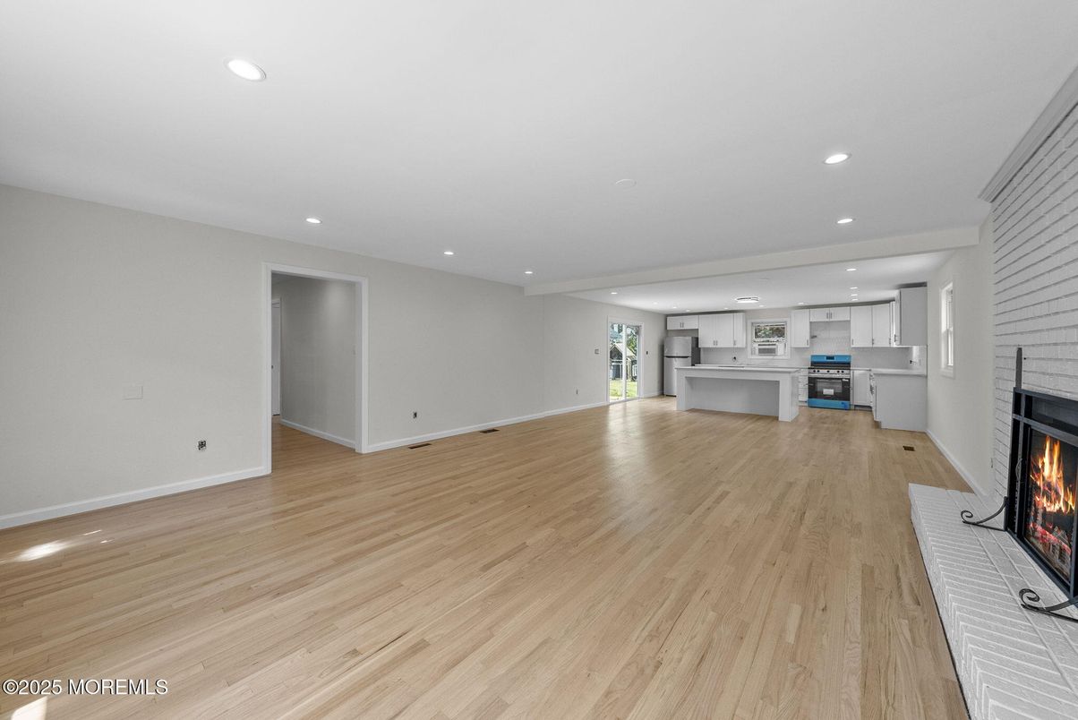 Empty room, Fireplace, Interior, Kitchen, Recessed Lighting, Stainless Steel Appliances, Wood Texture Flooring