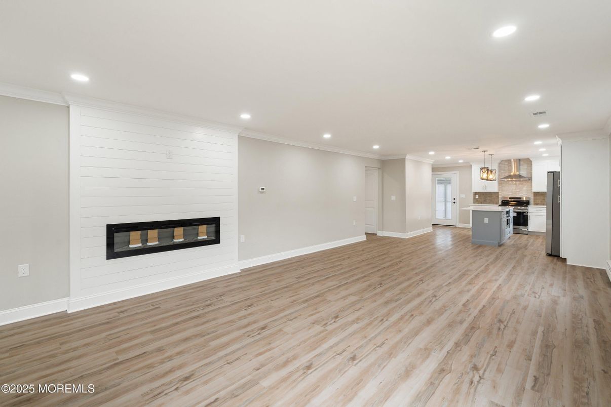 Empty room, Fireplace, Interior, Kitchen, Pendant Lights, Recessed Lighting, Stainless Steel Appliances, Wood Texture Flooring