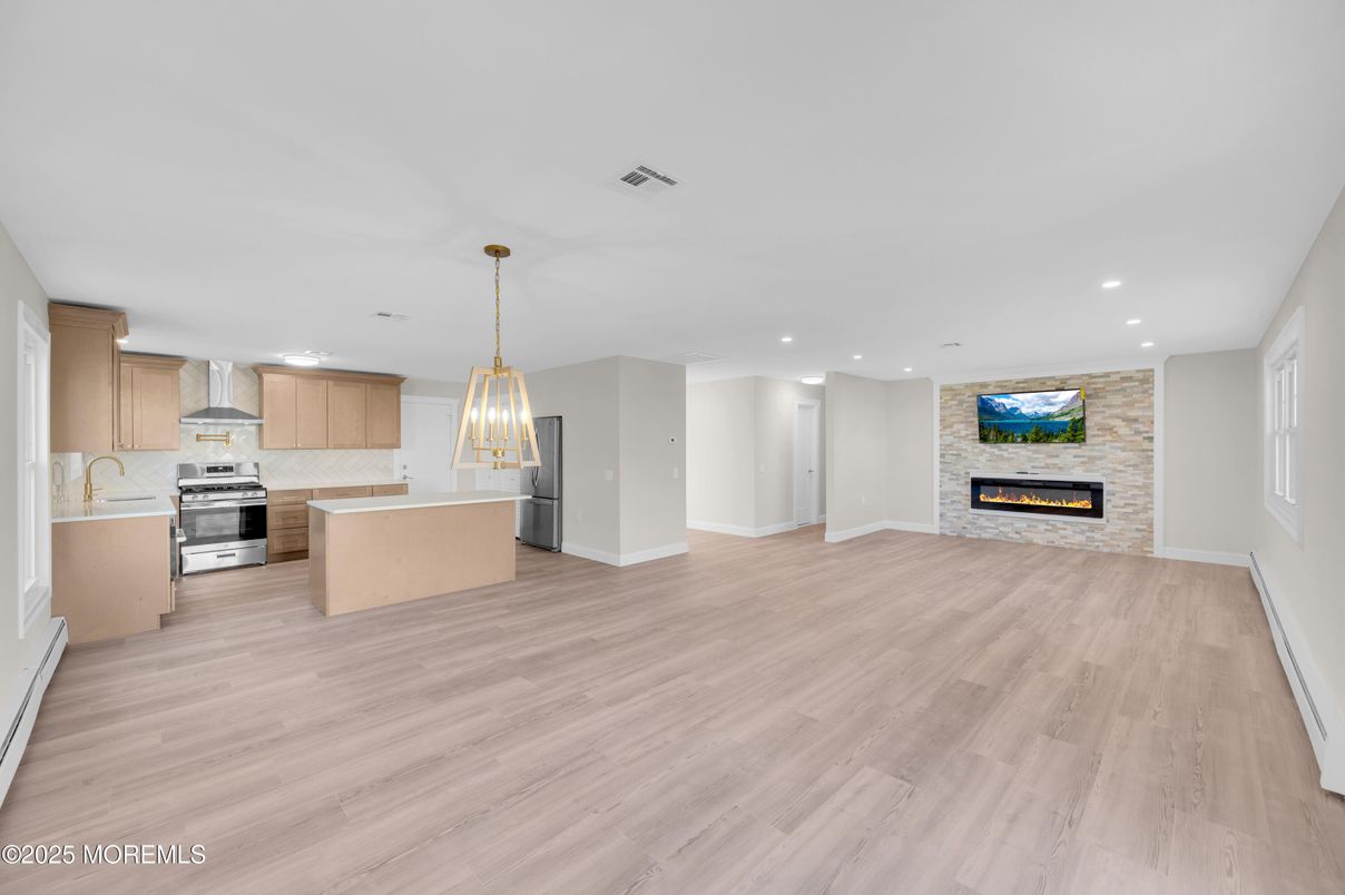 Empty room, Fireplace, Interior, Kitchen, Pendant Lights, Recessed Lighting, Stainless Steel Appliances, Wood Texture Flooring