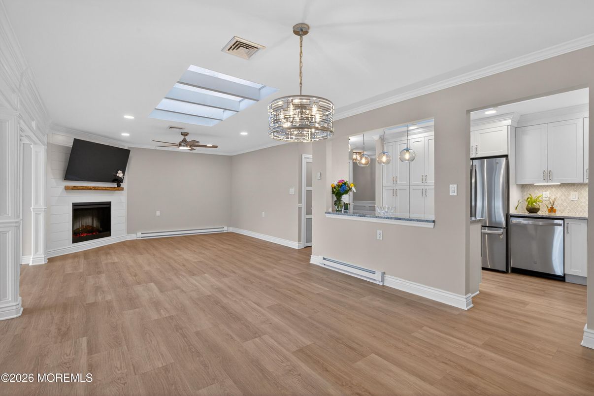 Chandelier, Empty room, Fireplace, Interior, Kitchen, Pendant Lights, Recessed Lighting, Stainless Steel Appliances, Wood Texture Flooring