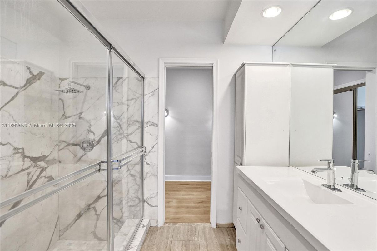 Bathroom, Dual Sink Vanities, Glass Shower, Interior, Marble Walls, Recessed Lighting, Wood Texture Flooring