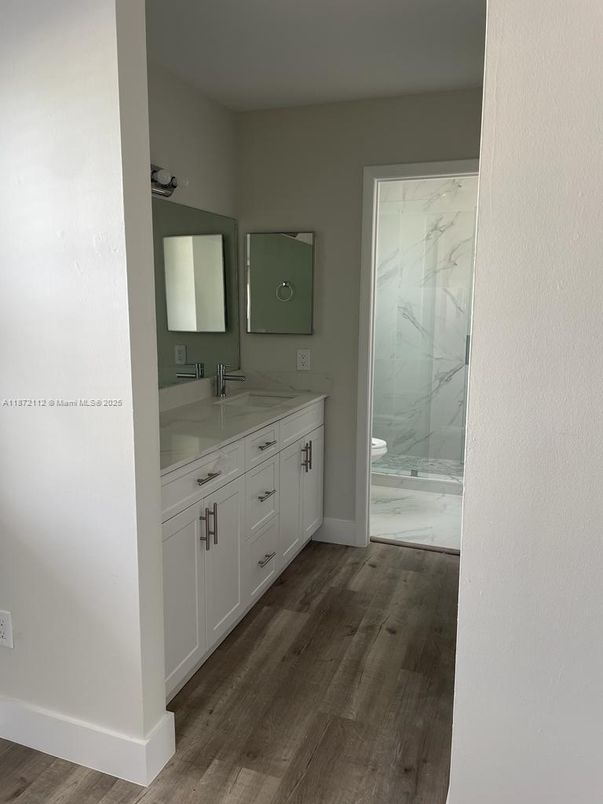 Bathroom, Dual Sink Vanities, Glass Shower, Interior, Marble Walls, Wood Texture Flooring