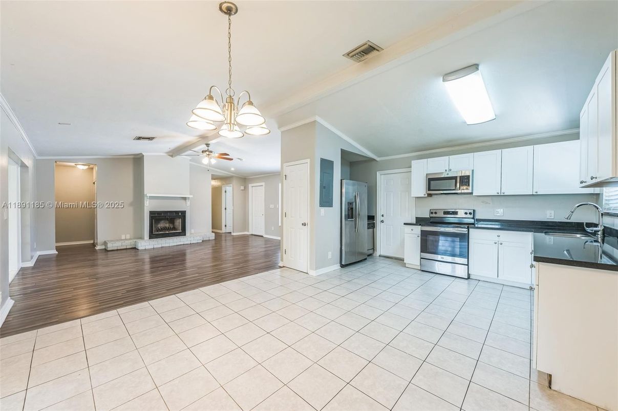 Chandelier, Empty room, Fireplace, Interior, Kitchen, Pendant Lights, Stainless Steel Appliances, Wood Texture Flooring