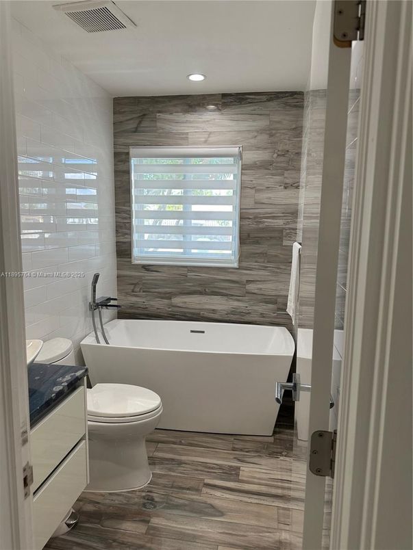 Bathroom, Free Standing Baths, Interior, Marble Walls, Recessed Lighting, Wood Texture Flooring, Wooden Walls