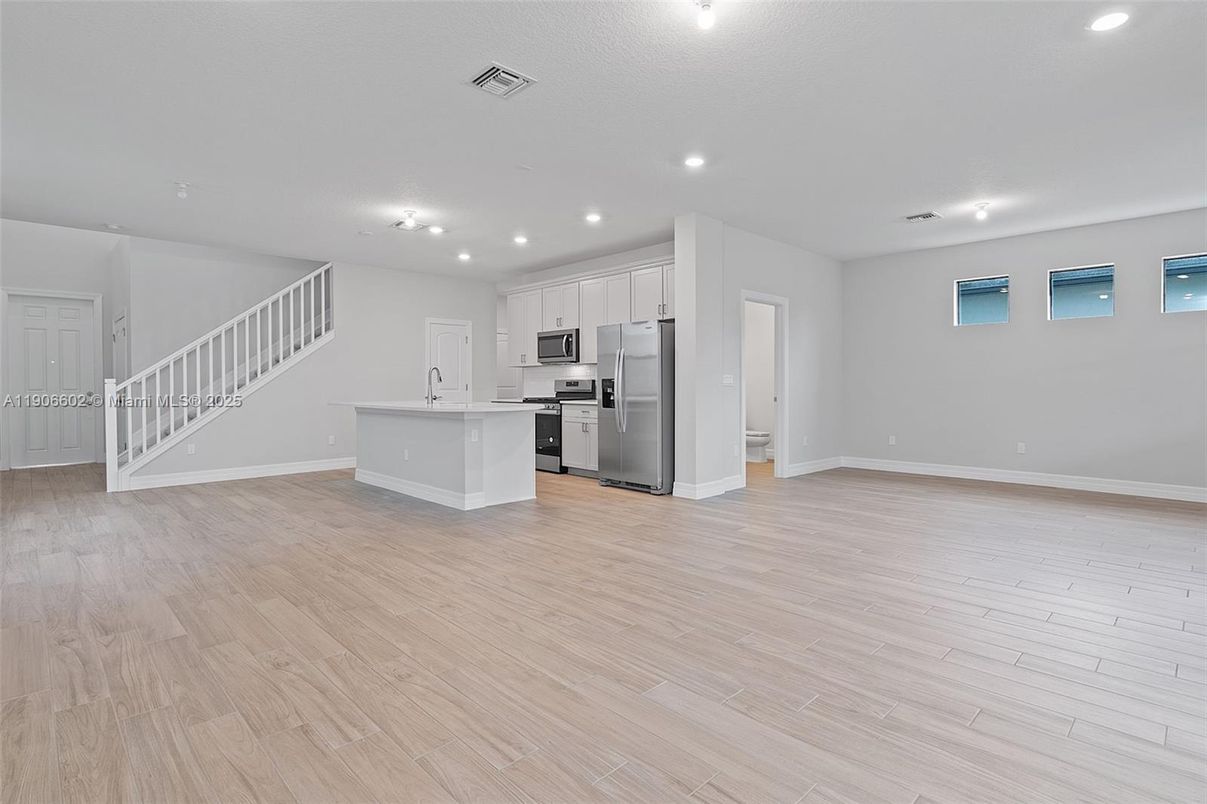 Empty room, Interior, Kitchen, Recessed Lighting, Stainless Steel Appliances, Wood Texture Flooring