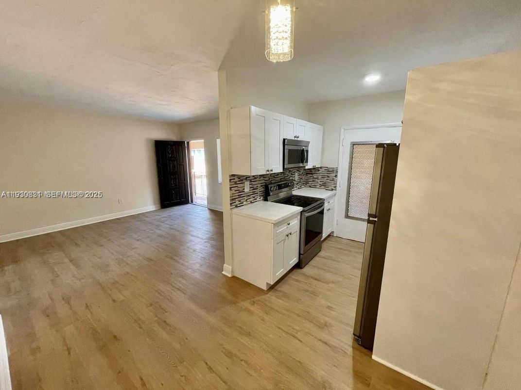 Empty room, Interior, Kitchen, Recessed Lighting, Stainless Steel Appliances, Wood Texture Flooring