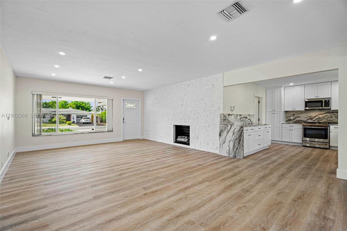 Empty room, Fireplace, Interior, Kitchen, Recessed Lighting, Stainless Steel Appliances, Stone Walls, Wood Texture Flooring