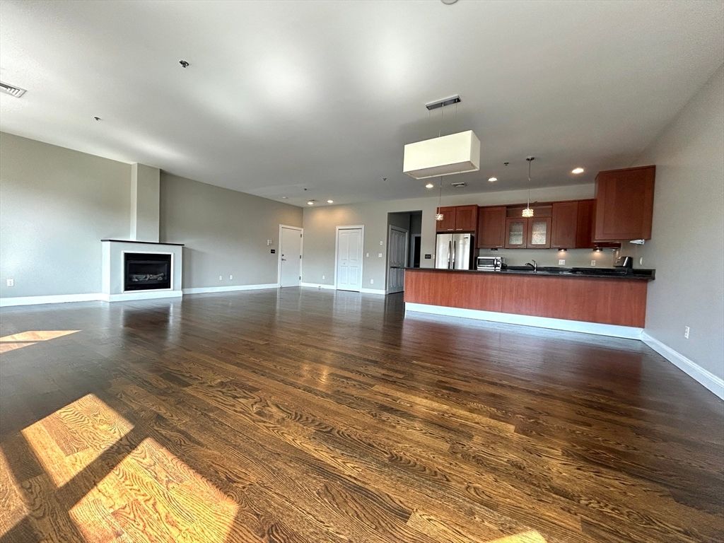 Empty room, Fireplace, Interior, Kitchen, Pendant Lights, Recessed Lighting, Stainless Steel Appliances, Wood Texture Flooring