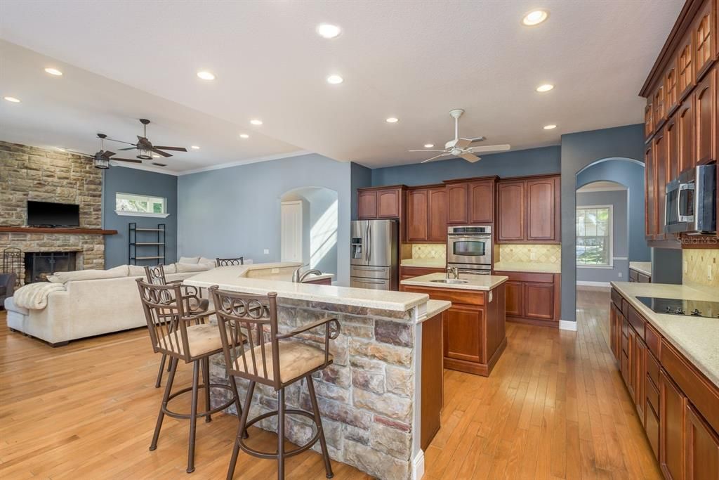 Fireplace, Interior, Kitchen, Living room, Recessed Lighting, Stainless Steel Appliances, Stone Walls, Wood Texture Flooring