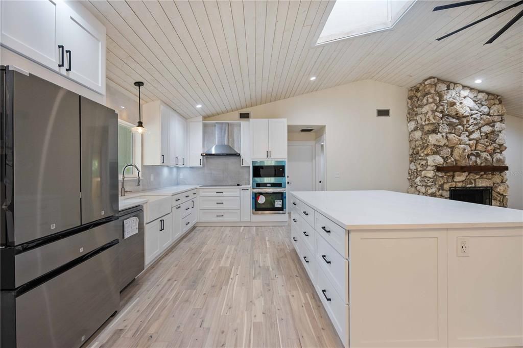 Fireplace, Interior, Kitchen, Pendant Lights, Recessed Lighting, Stainless Steel Appliances, Stone Walls, Wood Texture Flooring