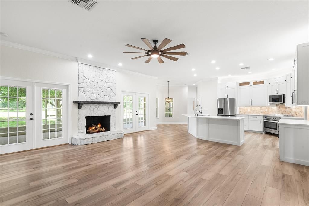 Empty room, Fireplace, Interior, Kitchen, Pendant Lights, Recessed Lighting, Stainless Steel Appliances, Stone Walls, Wood Texture Flooring