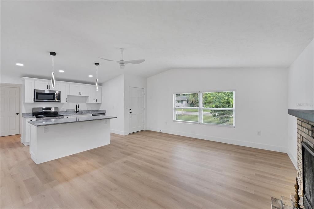 Empty room, Fireplace, Interior, Kitchen, Pendant Lights, Recessed Lighting, Stainless Steel Appliances, Wood Texture Flooring