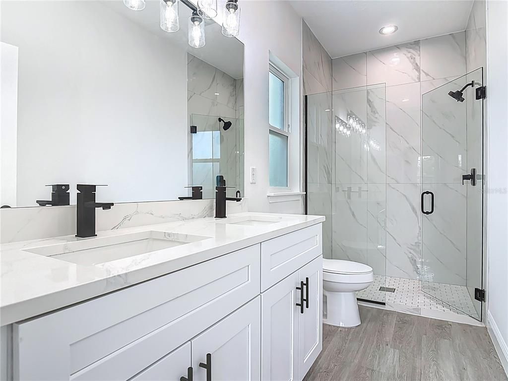 Bathroom, Dual Sink Vanities, Glass Shower, Interior, Marble Walls, Recessed Lighting, Wood Texture Flooring
