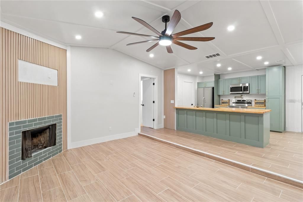 Empty room, Fireplace, Interior, Kitchen, Recessed Lighting, Stainless Steel Appliances, Wood Texture Flooring