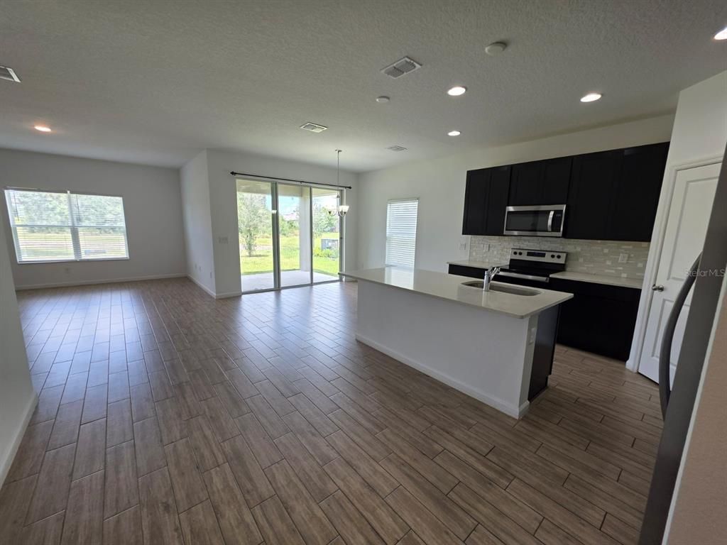 Empty room, Interior, Kitchen, Pendant Lights, Recessed Lighting, Stainless Steel Appliances, Wood Texture Flooring