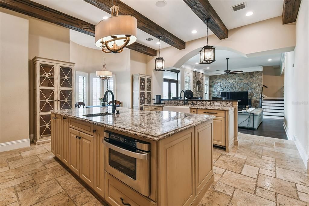 Chandelier, Fireplace, Interior, Kitchen, Living room, Pendant Lights, Recessed Lighting, Stainless Steel Appliances, Stone Walls, Wooden Beams