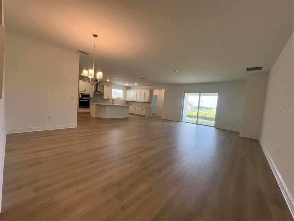 Chandelier, Empty room, Interior, Kitchen, Pendant Lights, Recessed Lighting, Stainless Steel Appliances, Wood Texture Flooring