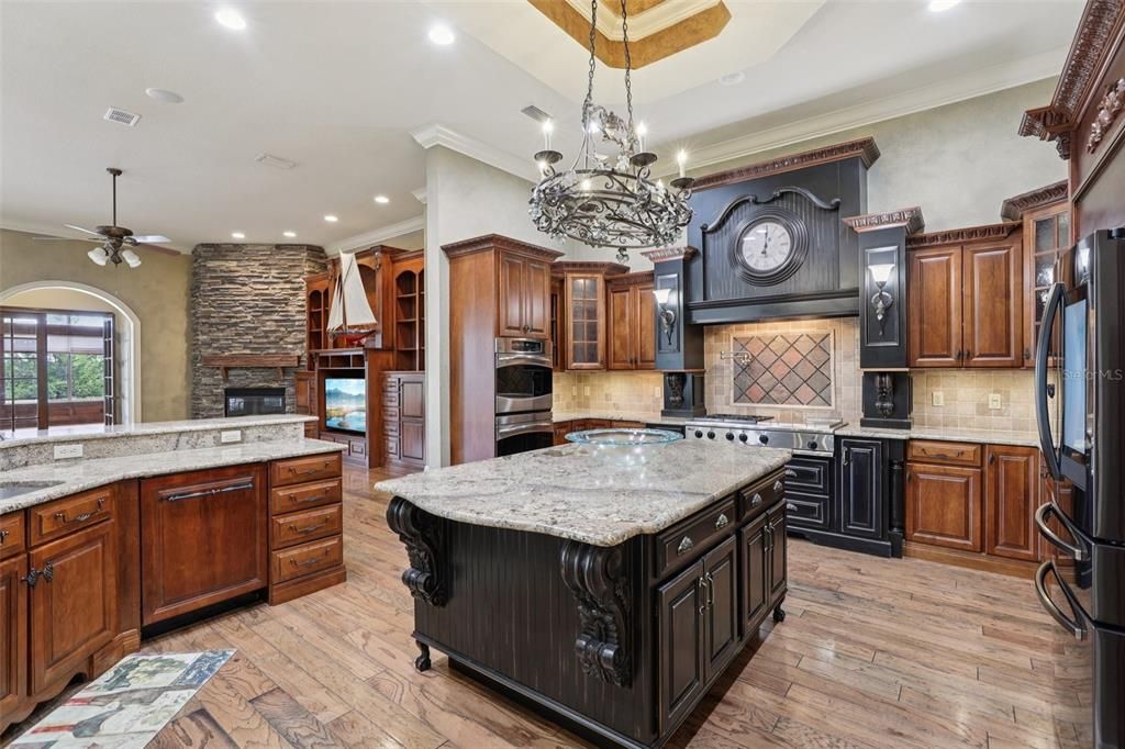 Chandelier, Fireplace, Interior, Kitchen, Pendant Lights, Recessed Lighting, Stainless Steel Appliances, Stone Walls, Wood Texture Flooring