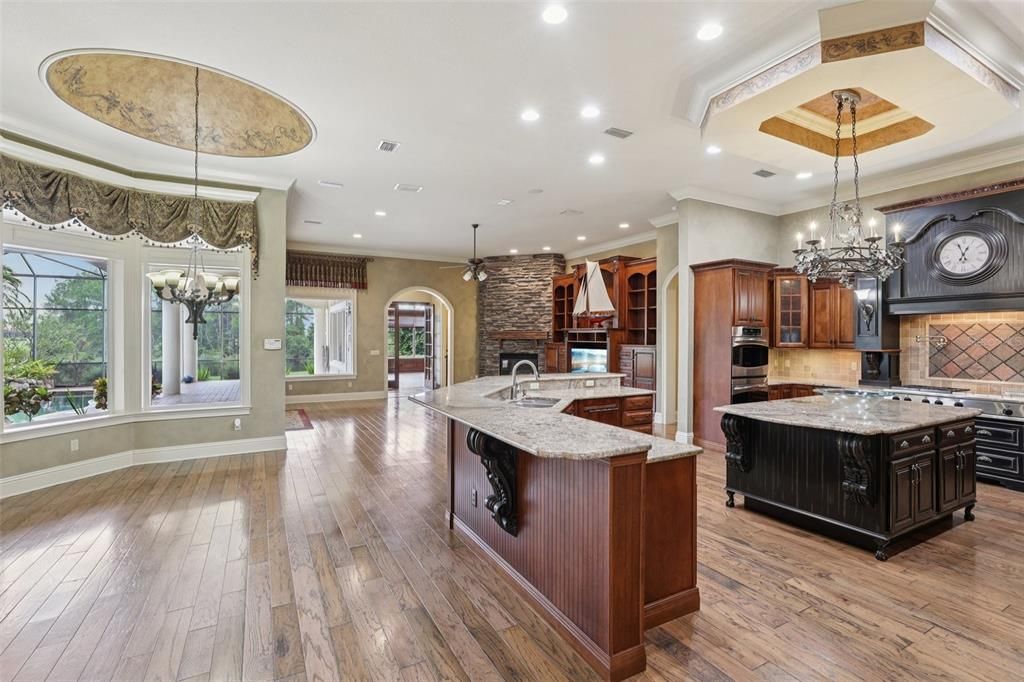 Chandelier, Fireplace, Interior, Kitchen, Pendant Lights, Recessed Lighting, Stainless Steel Appliances, Stone Walls, Wood Texture Flooring