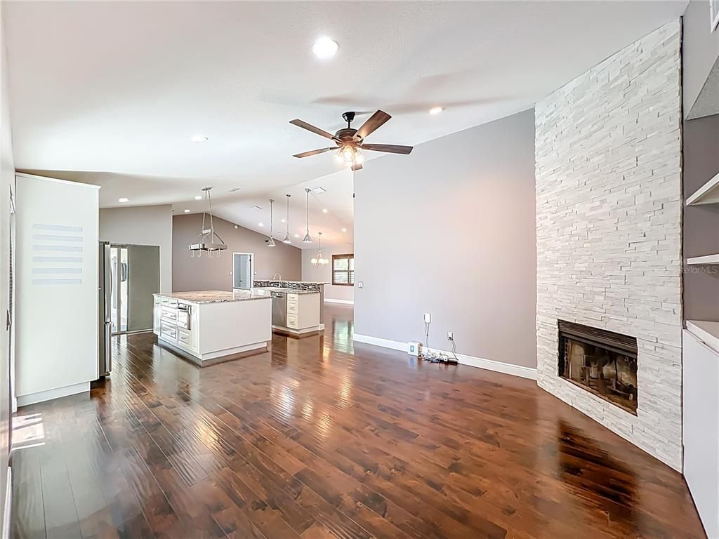 Empty room, Fireplace, Interior, Kitchen, Pendant Lights, Recessed Lighting, Stainless Steel Appliances, Stone Walls, Wood Texture Flooring