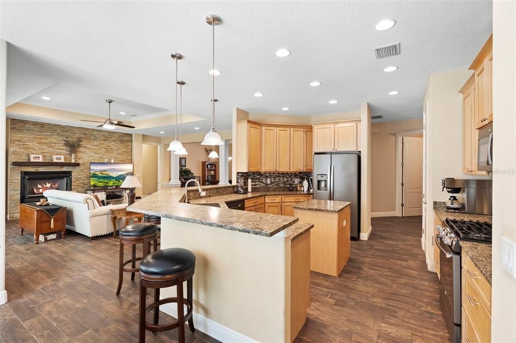 Fireplace, Interior, Kitchen, Living room, Pendant Lights, Recessed Lighting, Stainless Steel Appliances, Stone Walls, Wood Texture Flooring