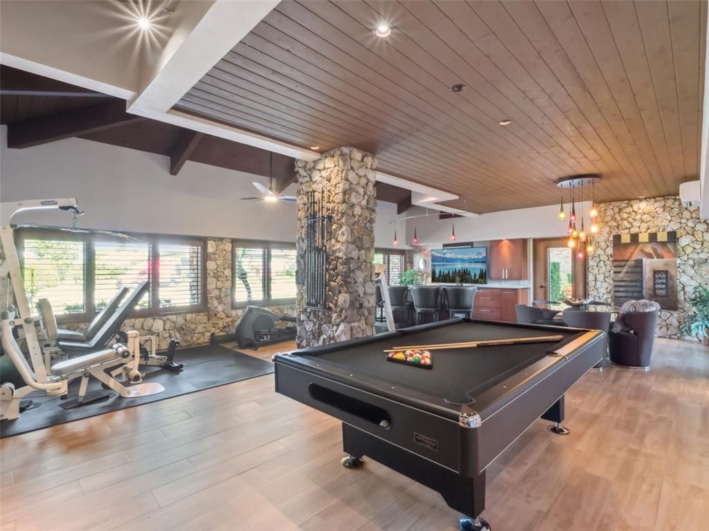 Billiard Table, Fireplace, Fitness Equipment, Game Room, Interior, Pendant Lights, Recessed Lighting, Stone Walls, Wooden Ceilings, Wood Texture Flooring