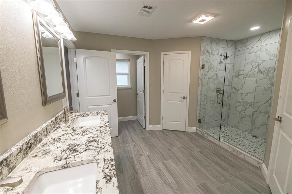 Bathroom, Dual Sink Vanities, Glass Shower, Interior, Marble Walls, Recessed Lighting, Wood Texture Flooring