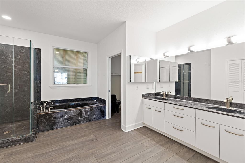 Bathroom, Dual Sink Vanities, Glass Shower, Interior, Marble Walls, Recessed Lighting, Wood Texture Flooring
