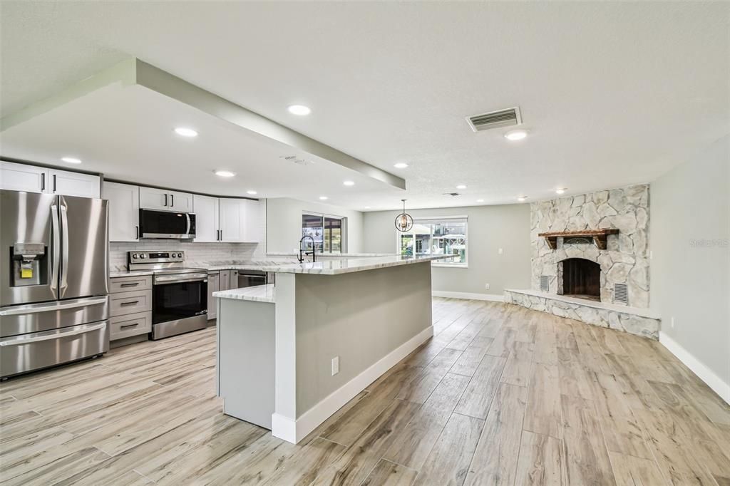 Fireplace, Interior, Kitchen, Recessed Lighting, Stainless Steel Appliances, Stone Walls, Wood Texture Flooring