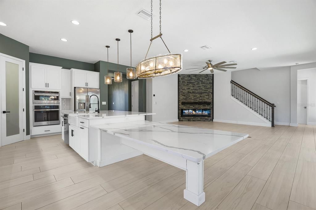 Fireplace, Interior, Kitchen, Pendant Lights, Recessed Lighting, Stainless Steel Appliances, Stone Walls, Wood Texture Flooring