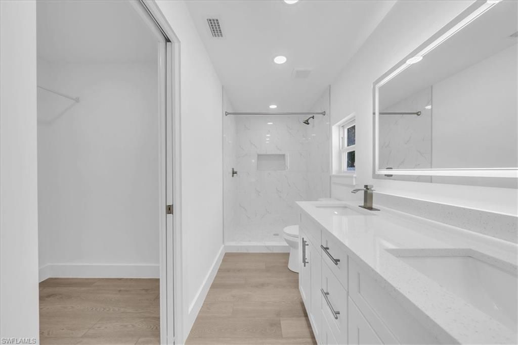 Bathroom, Dual Sink Vanities, Glass Shower, Interior, Marble Walls, Recessed Lighting, Wood Texture Flooring
