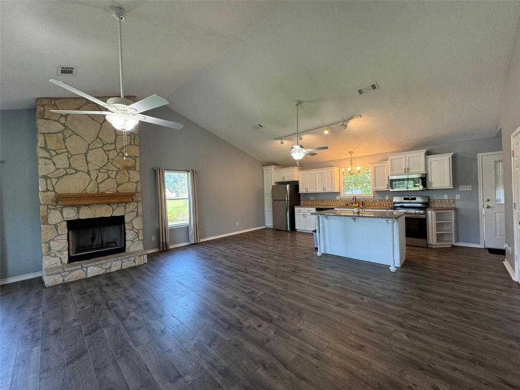 Empty room, Fireplace, Interior, Kitchen, Pendant Lights, Stainless Steel Appliances, Stone Walls, Wood Texture Flooring