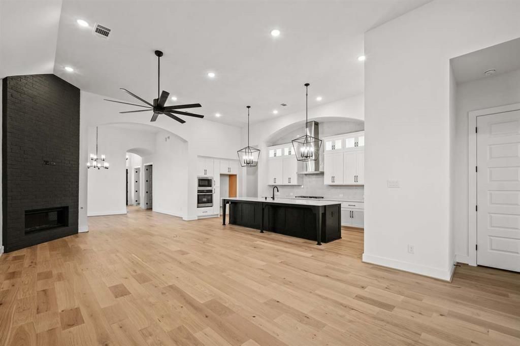 Chandelier, Empty room, Fireplace, Interior, Kitchen, Pendant Lights, Recessed Lighting, Stainless Steel Appliances, Wood Texture Flooring