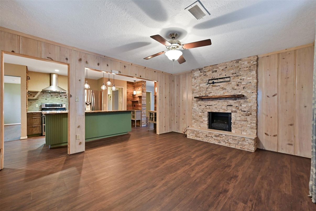 Empty room, Fireplace, Interior, Kitchen, Pendant Lights, Recessed Lighting, Stainless Steel Appliances, Stone Walls, Wood Texture Flooring, Wooden Walls