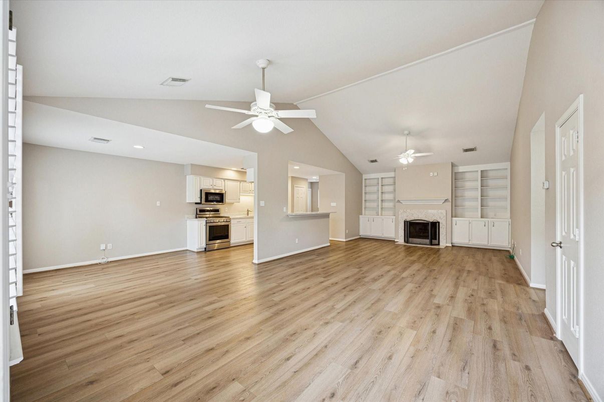Empty room, Fireplace, Interior, Kitchen, Recessed Lighting, Stainless Steel Appliances, Wood Texture Flooring