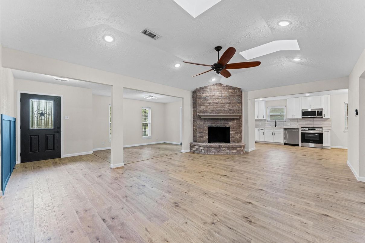 Empty room, Fireplace, Interior, Kitchen, Recessed Lighting, Stainless Steel Appliances, Stone Walls, Wood Texture Flooring