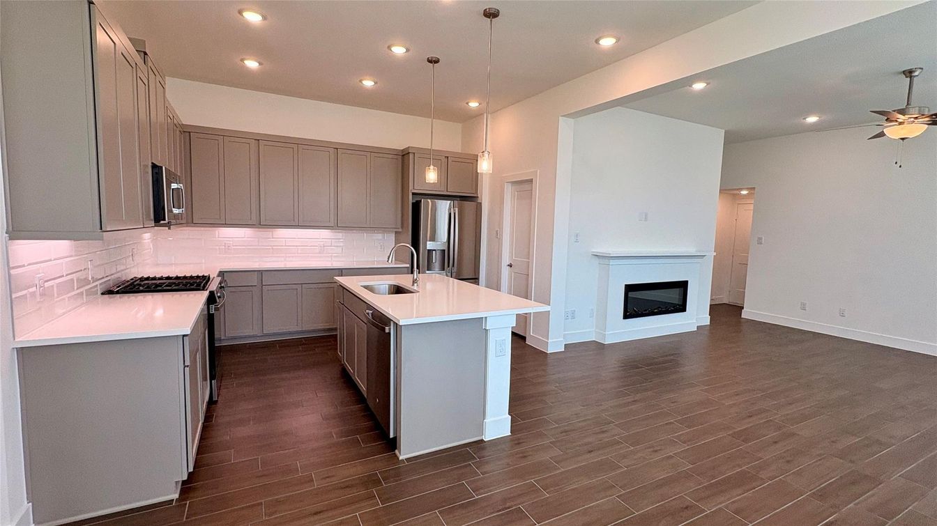 Empty room, Fireplace, Interior, Kitchen, Pendant Lights, Recessed Lighting, Stainless Steel Appliances, Wood Texture Flooring