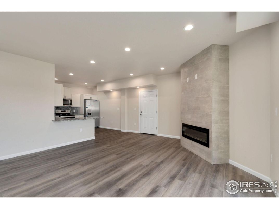 Empty room, Fireplace, Interior, Kitchen, Recessed Lighting, Stainless Steel Appliances, Wood Texture Flooring