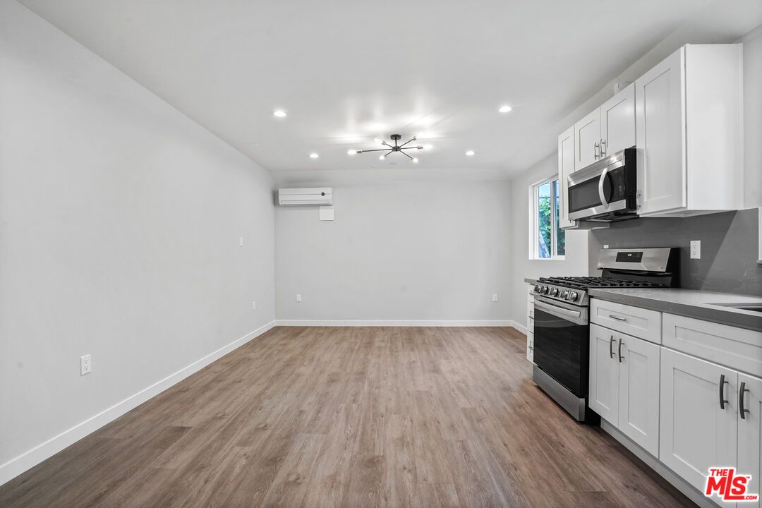 Empty room, Interior, Kitchen, Recessed Lighting, Stainless Steel Appliances, Wood Texture Flooring