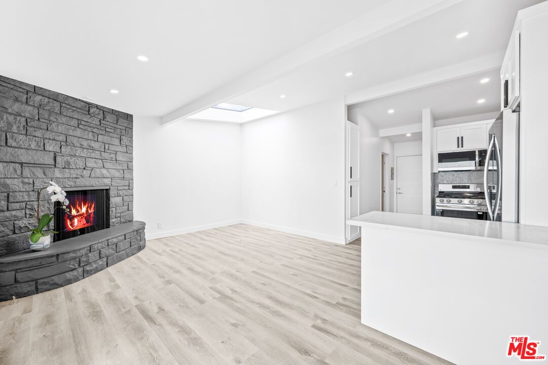 Empty room, Fireplace, Interior, Kitchen, Recessed Lighting, Stainless Steel Appliances, Stone Walls, Wood Texture Flooring