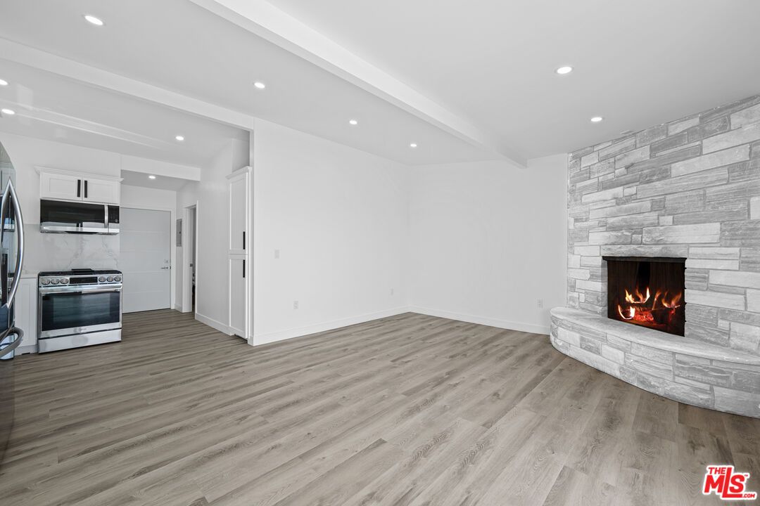 Empty room, Fireplace, Interior, Kitchen, Recessed Lighting, Stainless Steel Appliances, Stone Walls, Wood Texture Flooring