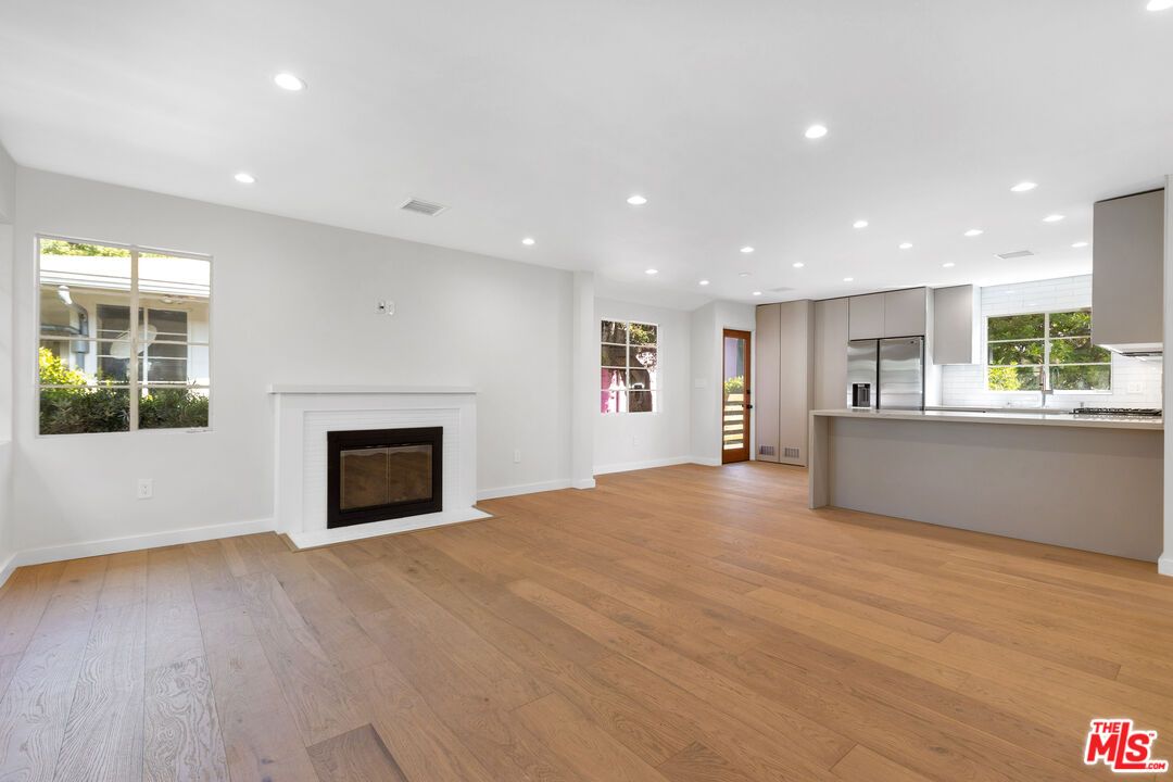 Empty room, Fireplace, Interior, Kitchen, Recessed Lighting, Stainless Steel Appliances, Wood Texture Flooring