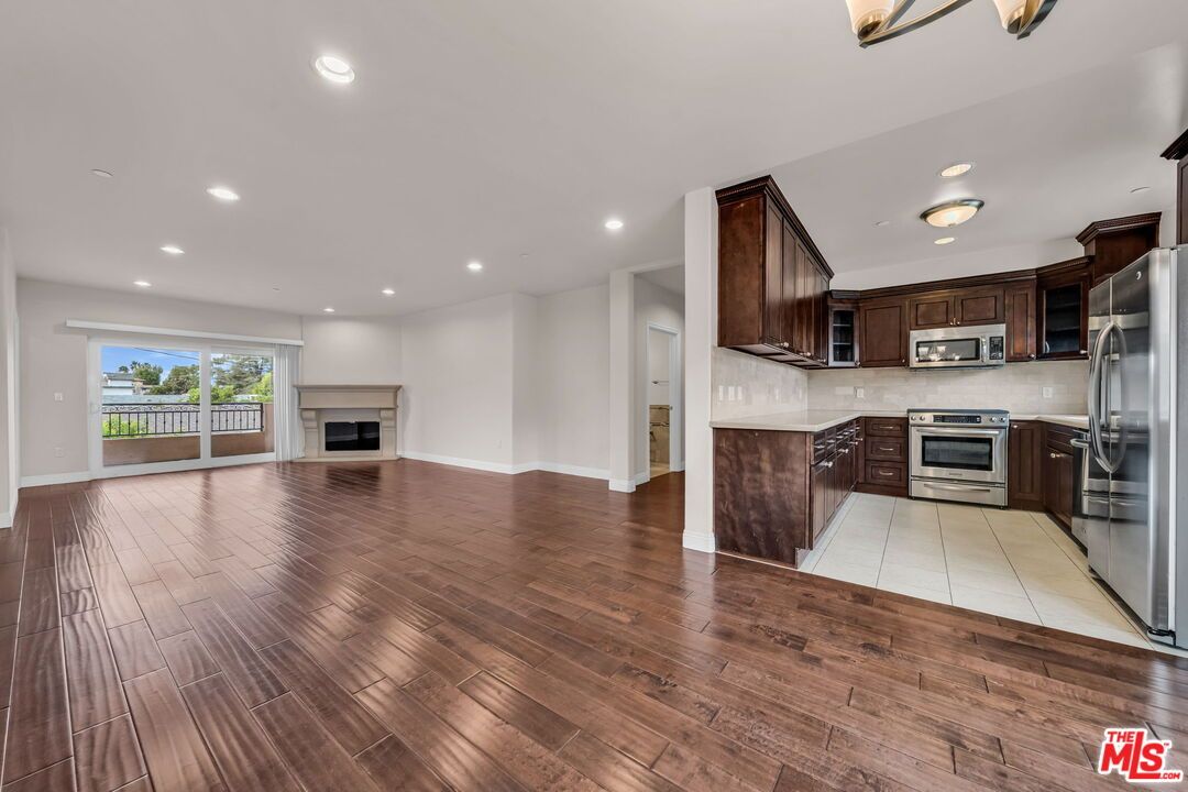 Empty room, Fireplace, Interior, Kitchen, Recessed Lighting, Stainless Steel Appliances, Wood Texture Flooring