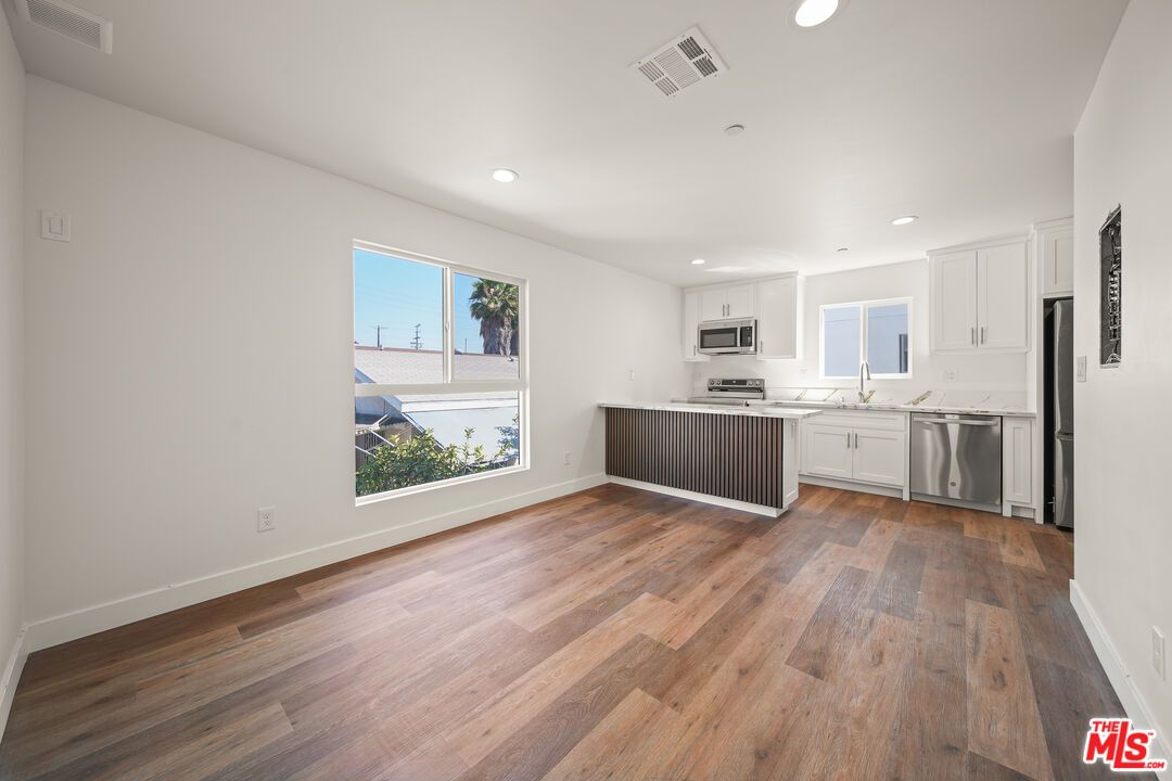 Empty room, Interior, Kitchen, Recessed Lighting, Stainless Steel Appliances, Wood Texture Flooring