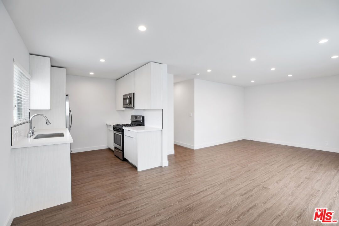 Empty room, Interior, Kitchen, Recessed Lighting, Stainless Steel Appliances, Wood Texture Flooring