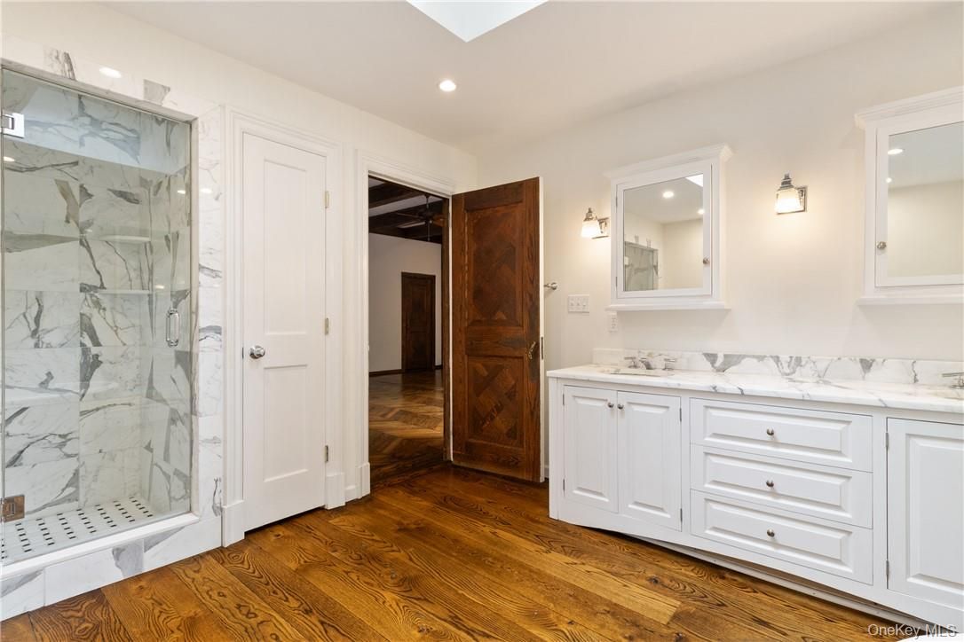 Bathroom, Dual Sink Vanities, Glass Shower, Interior, Marble Walls, Recessed Lighting, Wood Texture Flooring