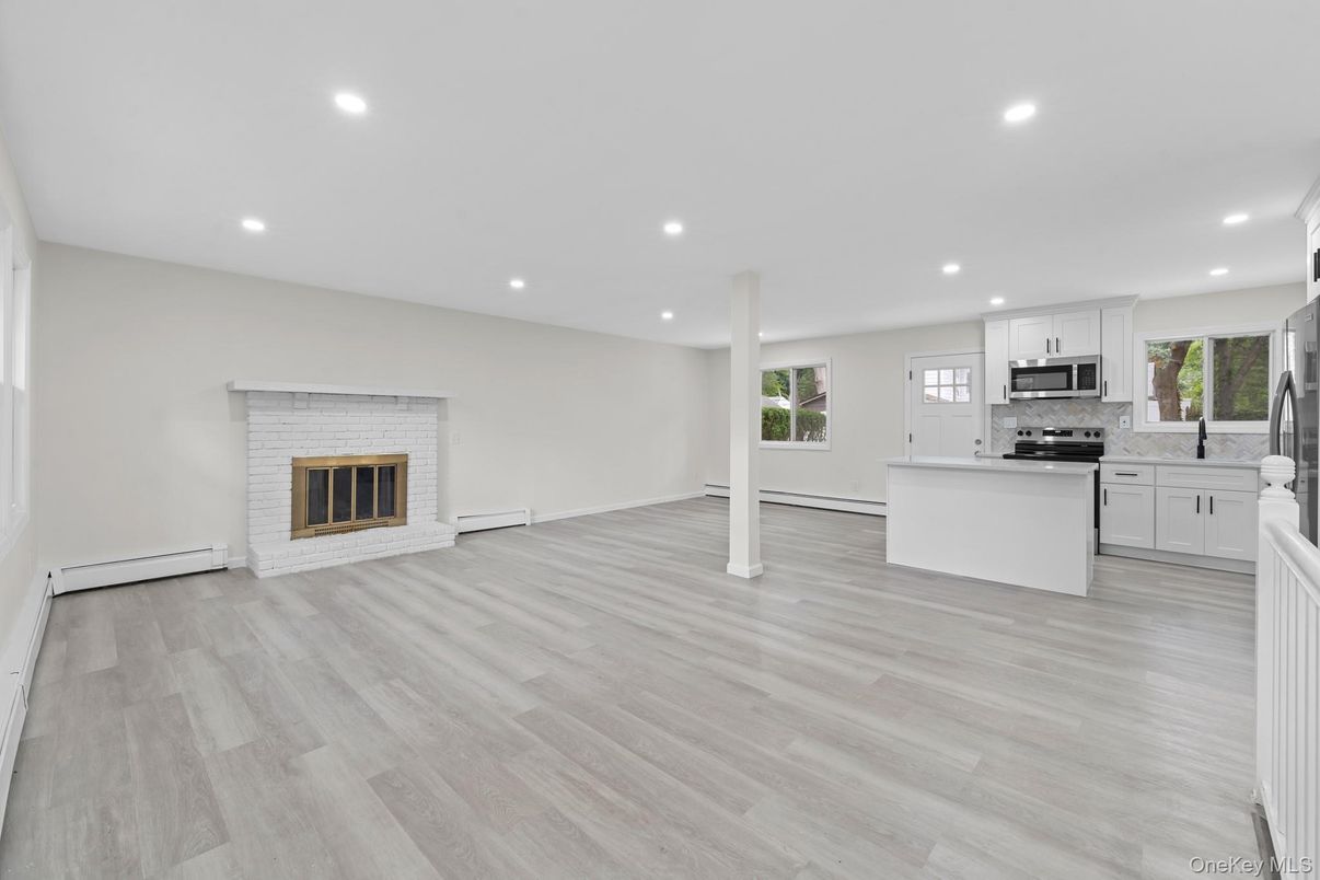 Empty room, Fireplace, Interior, Kitchen, Recessed Lighting, Stainless Steel Appliances, Wood Texture Flooring
